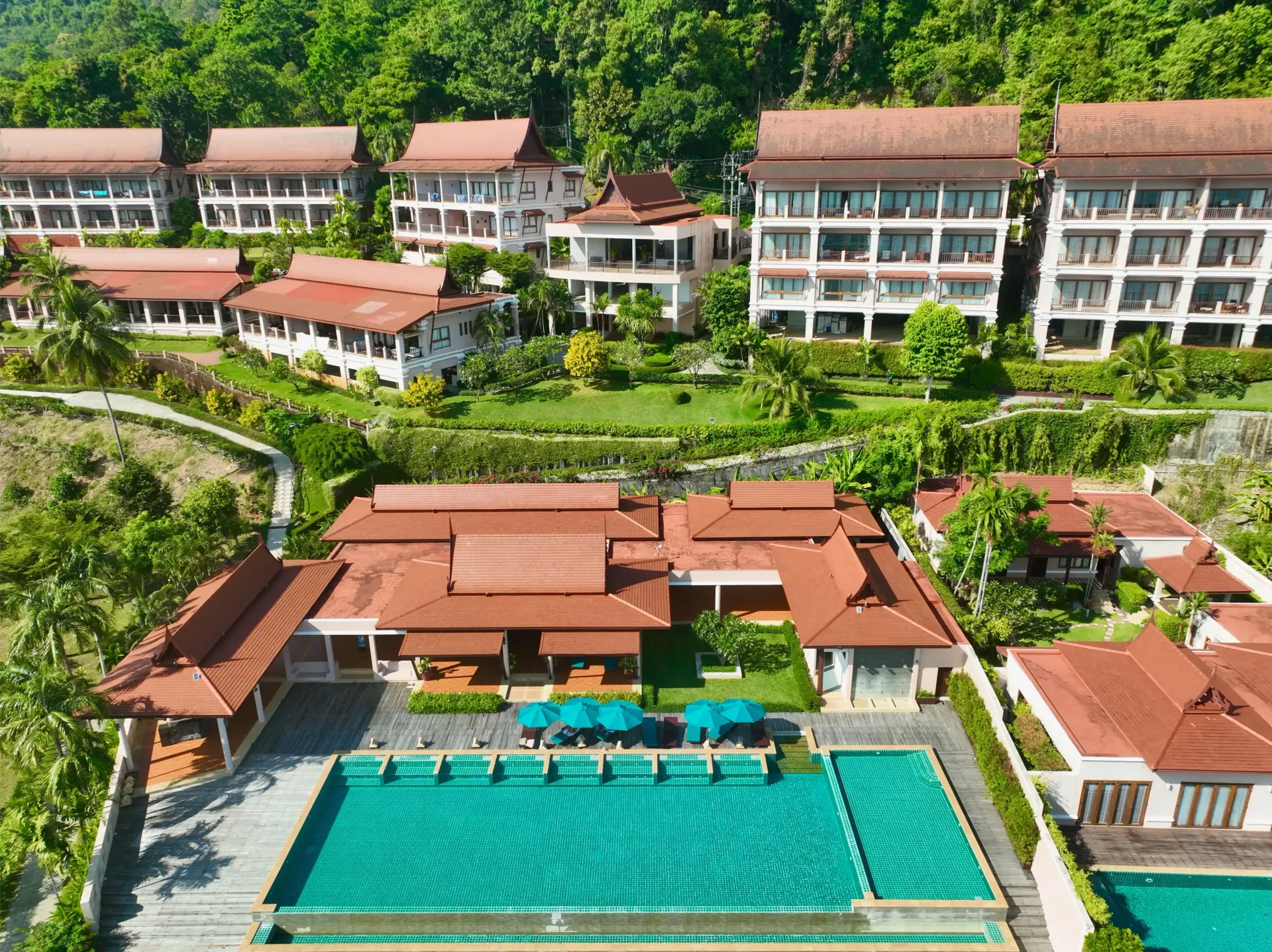An aerial view of a resort with a large swimming pool surrounded by buildings.