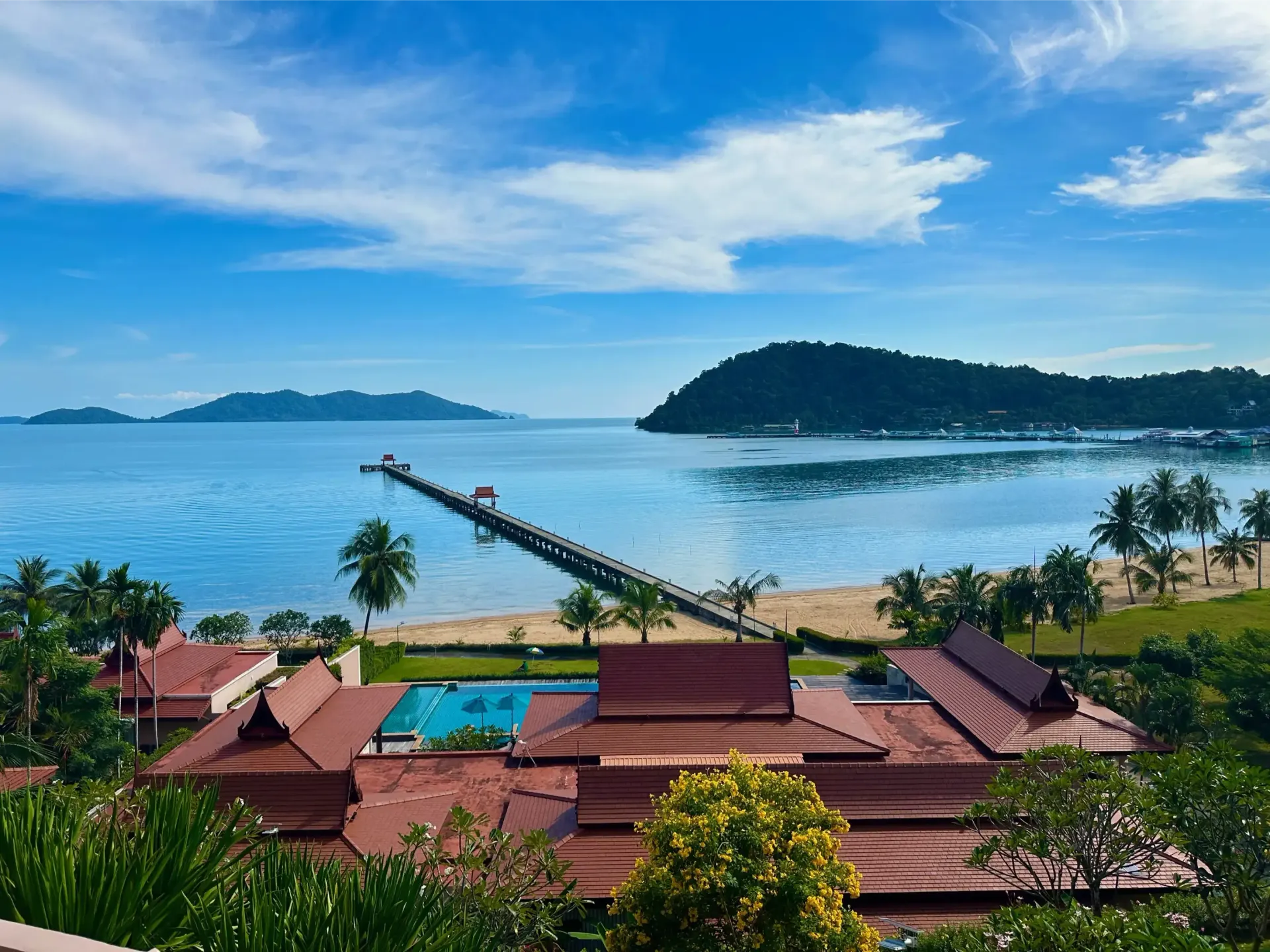 An aerial view of a resort with a pier leading to the ocean.