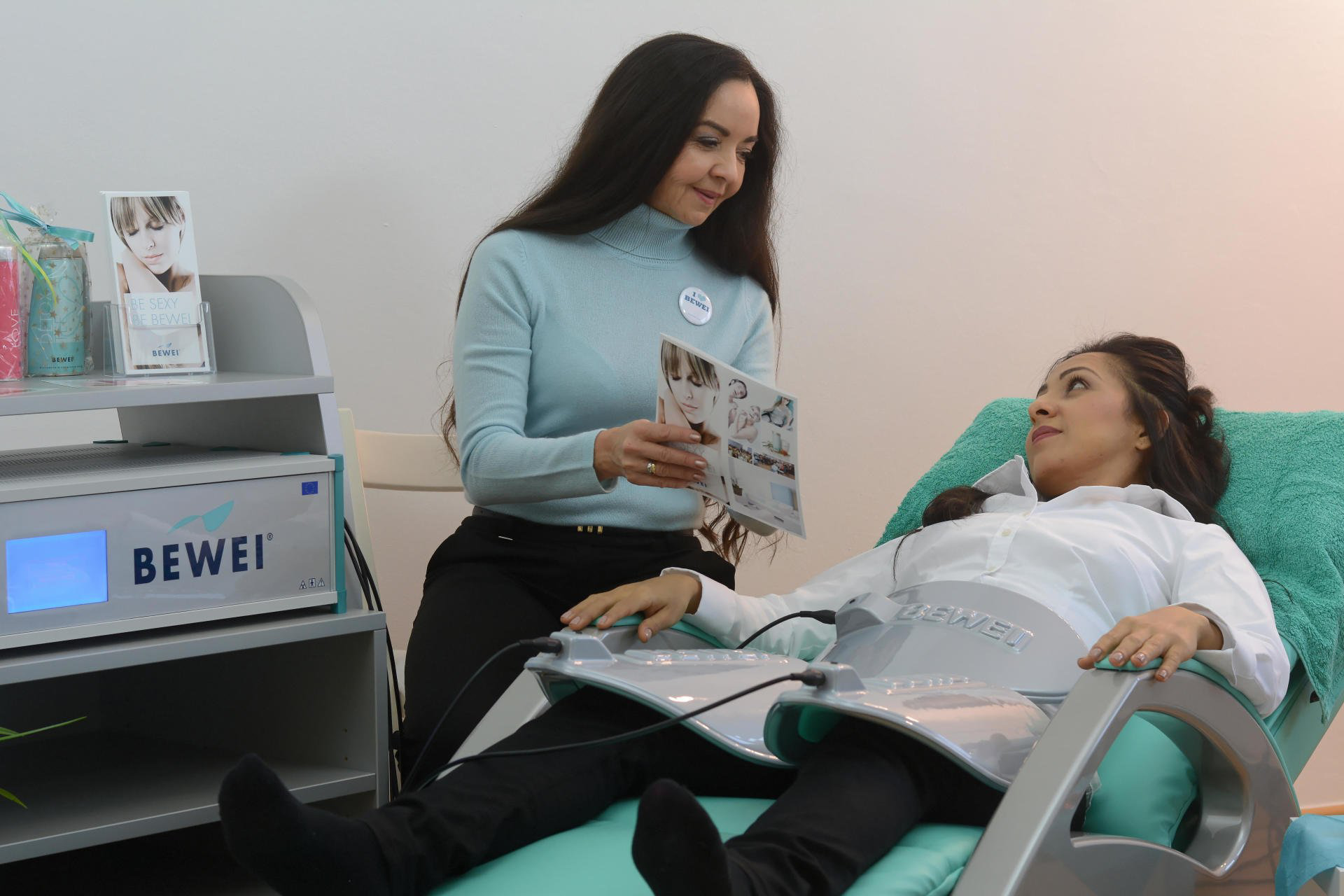 Eine Frau sitzt neben einer Frau, die auf einem Bett liegt.