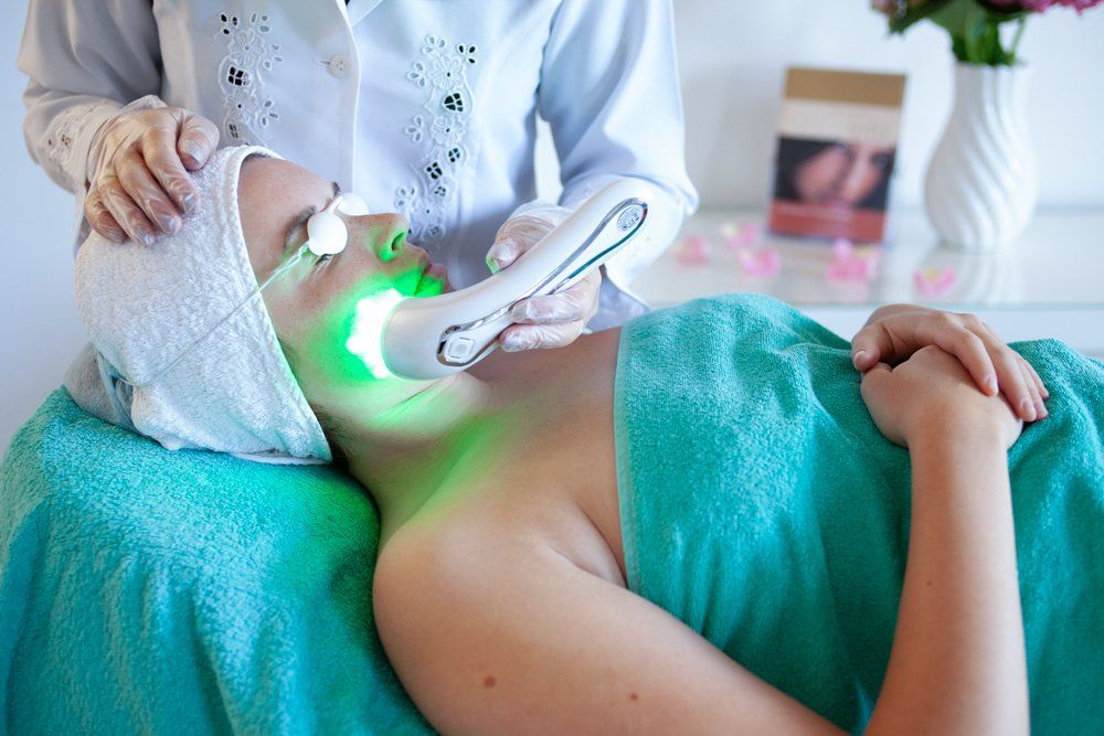 Eine Frau bekommt eine Grünlichtbehandlung im Gesicht.