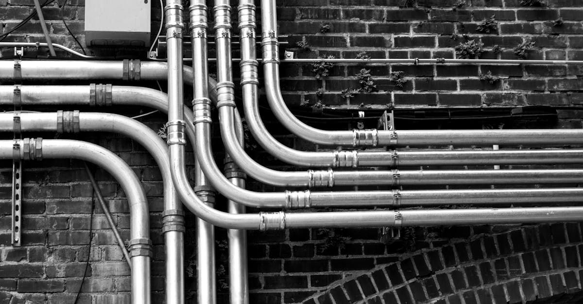 A black and white photo of a bunch of pipes on a brick wall.