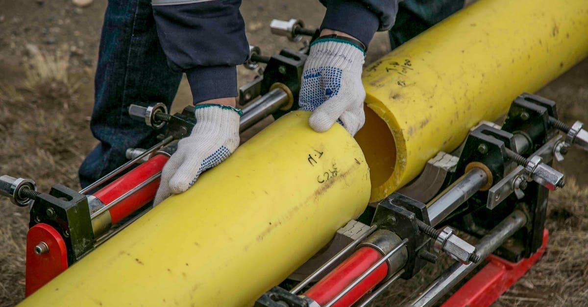 A man is working on a yellow pipe with a machine.