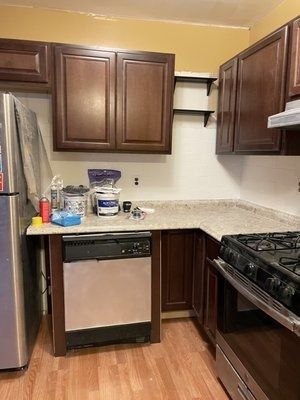 Kitchen with dark cabinets, a stainless steel dishwasher, and a stove.