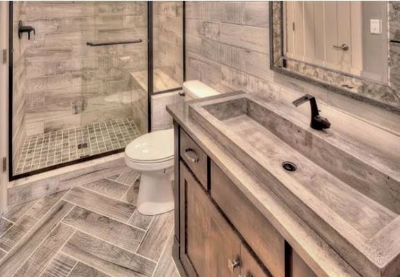 Bathroom with wood-look tile, glass shower, long rectangular sink, and wood vanity.