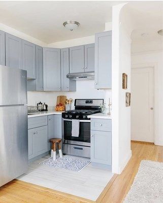Blue kitchen cabinets with stainless steel appliances and hardwood floors.