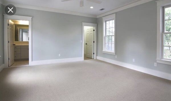 Empty bedroom with light blue walls, white trim, and beige carpet.