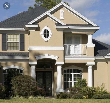 Beige two-story house with white trim and black shutters. A dark roof and manicured lawn.