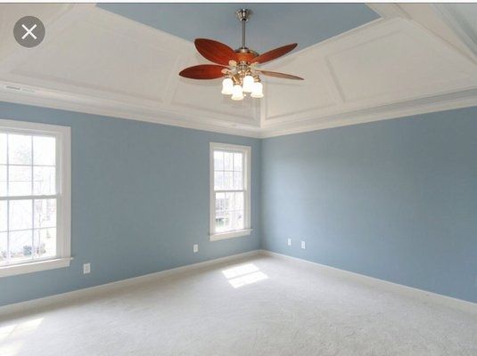 Empty bedroom with blue walls, white trim and ceiling, and two windows.