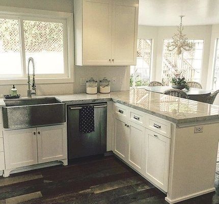 Bright white kitchen with stainless steel sink, cabinetry, and island with marble countertop.