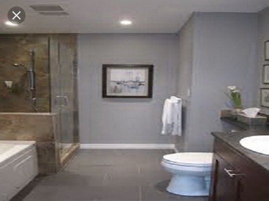 Gray bathroom with a shower, toilet, vanity, and artwork.