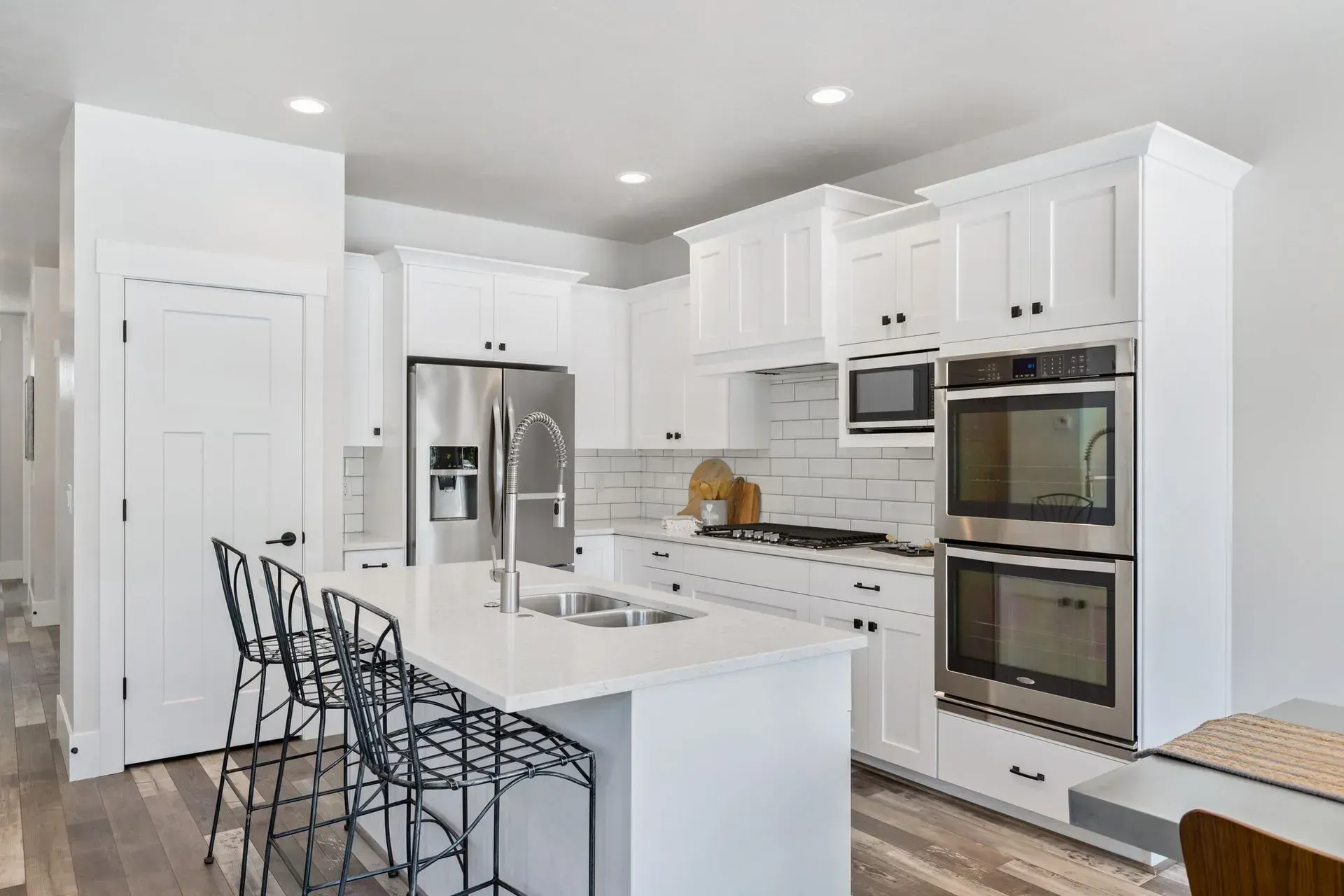 A kitchen with white cabinets , stainless steel appliances , and a large island.