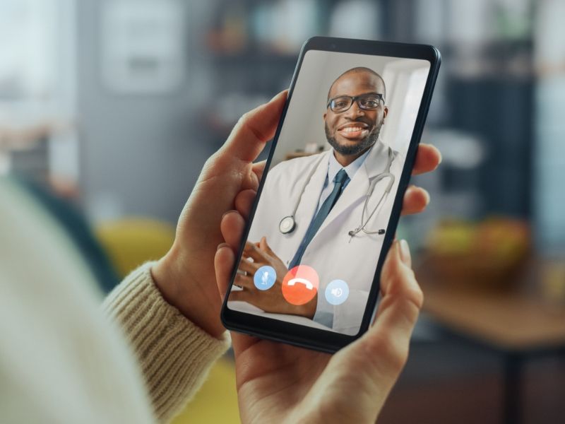 Uma pessoa está segurando um celular com um médico na tela.