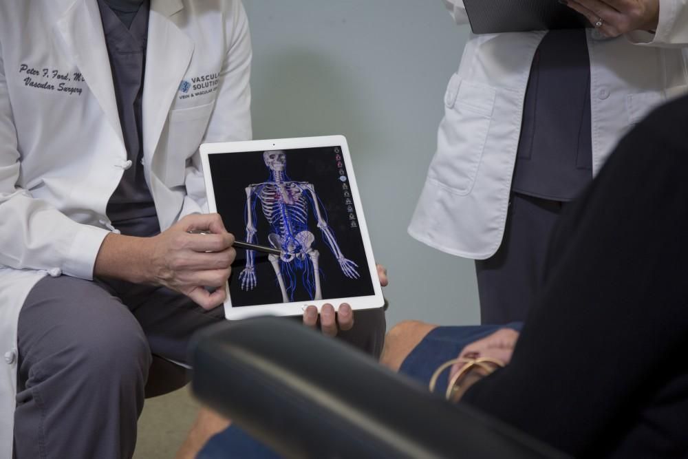 A doctor is holding a tablet with a picture of a skeleton on it.