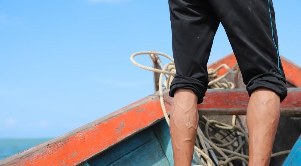 A man is standing on the side of a boat.