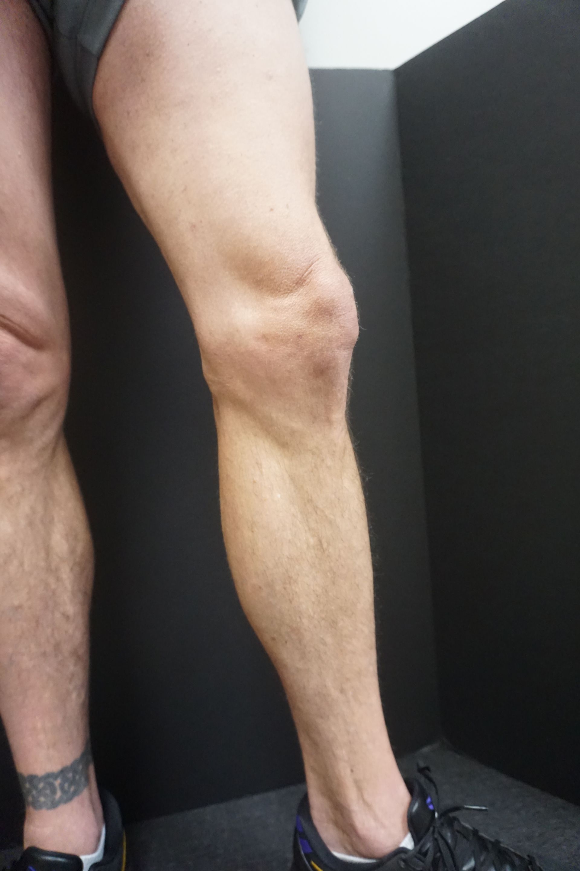 A man in blue underwear is standing with his legs crossed.