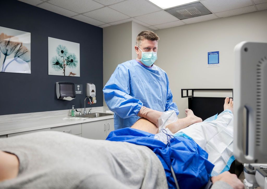 A doctor is giving a patient an ultrasound in a hospital room.