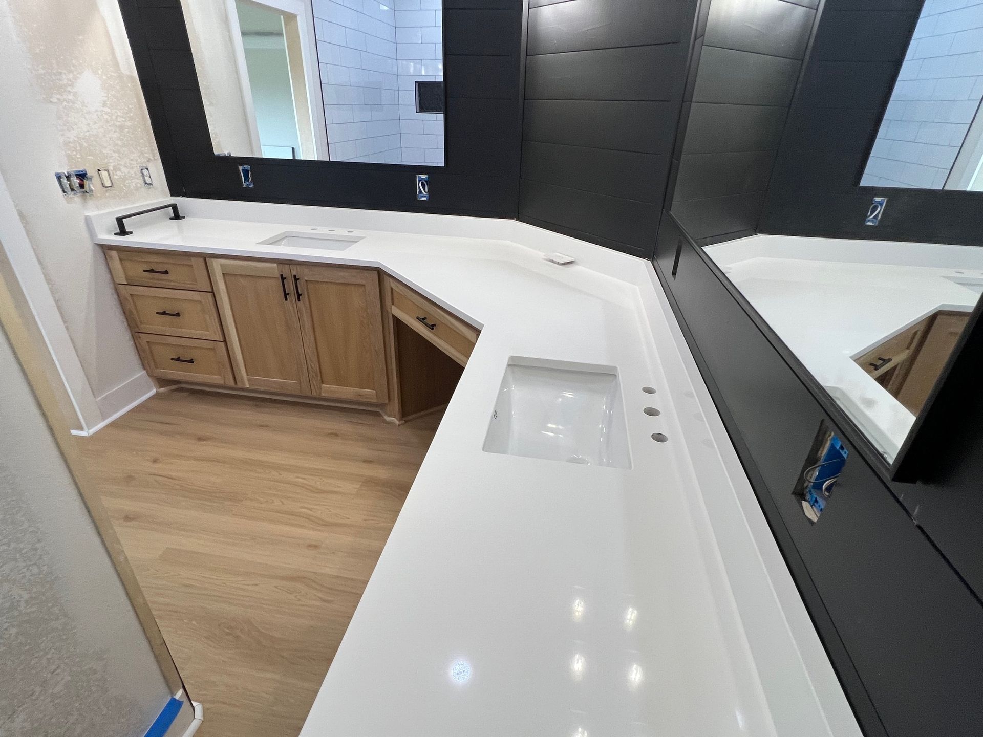 Bathroom with white countertops, black-framed mirrors, wooden cabinets, and a white sink.