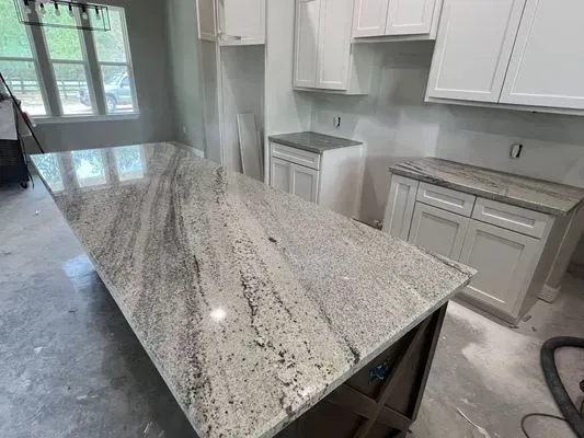 Kitchen with a large granite island and white cabinets.