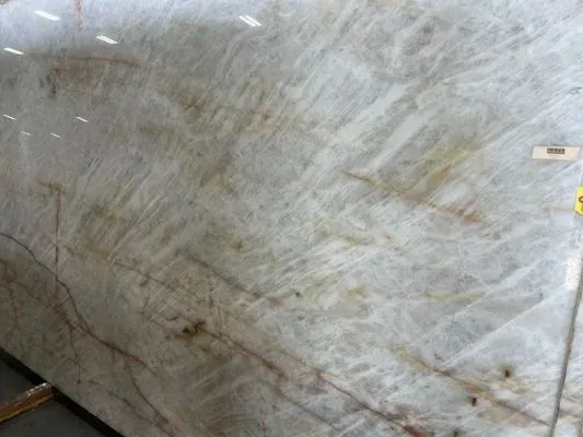 Large slab of white and beige granite with swirling patterns and brown veins.