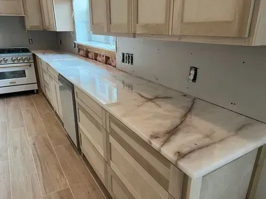 Kitchen with light wood cabinets and a white countertop with brown veining.
