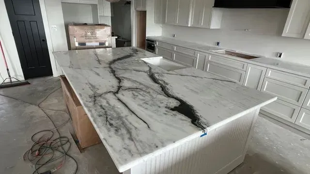 Kitchen with a white island and countertops, featuring black and gray veining, along with white cabinets.