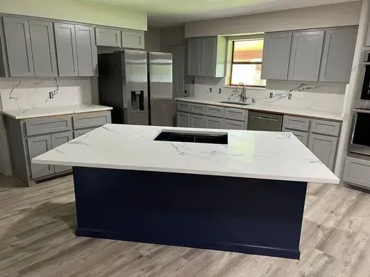 Modern kitchen with gray cabinets, white countertops, and a navy blue island.