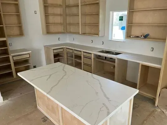 Kitchen with light wood cabinets, white countertops, and an island. Construction in progress.