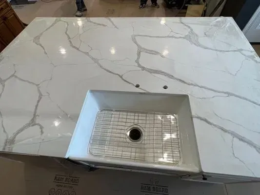 White quartz countertop with built-in sink and stainless steel grid.