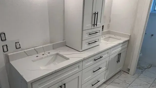 White bathroom vanity with marble countertop and storage cabinet.
