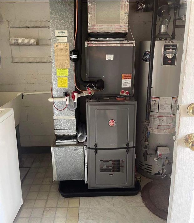 A laundry room with a furnace and water heater; gray appliances and a white laundry sink.