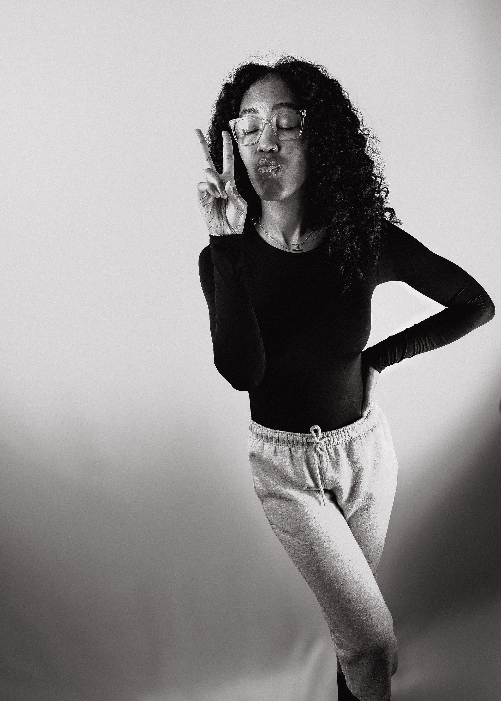 Close-up portrait of Hay Hay the Model highlighting her curly hair and stylish casual outfit in a well-lit studio.