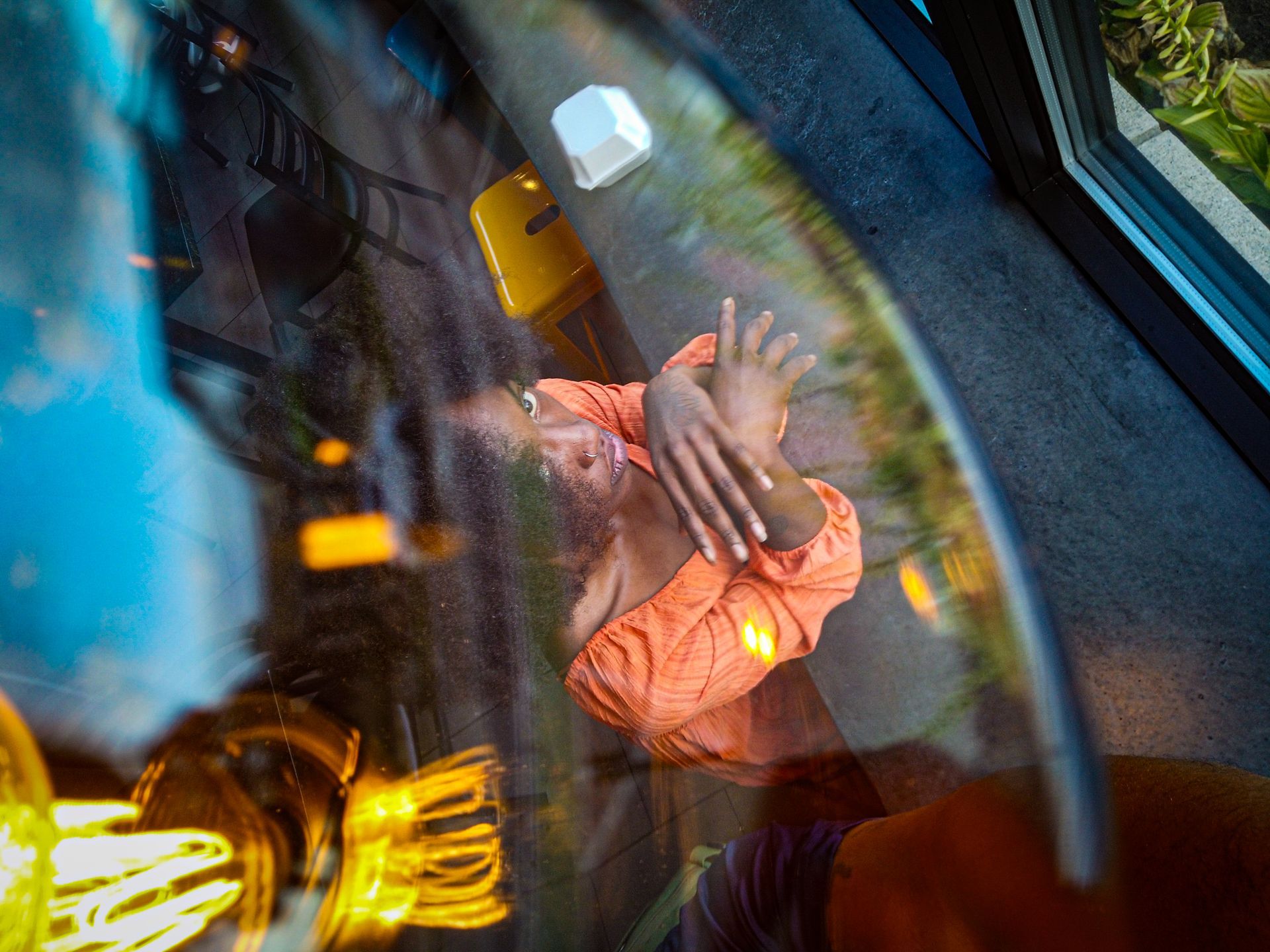 Close-up portrait of The Energetic Jay in an orange dress, highlighting her features and expression a colorful urban setting.