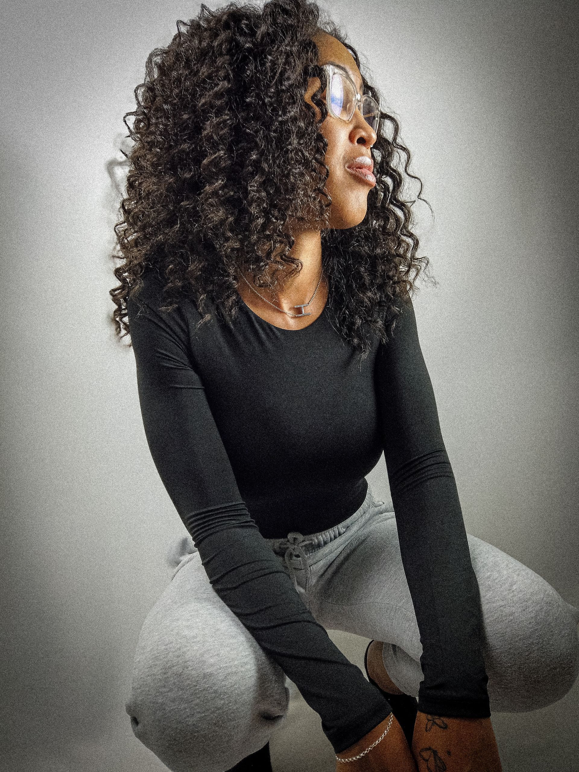 Hay Hay the Model posing in casual wear, showcasing her curly hair in a bright studio setting.