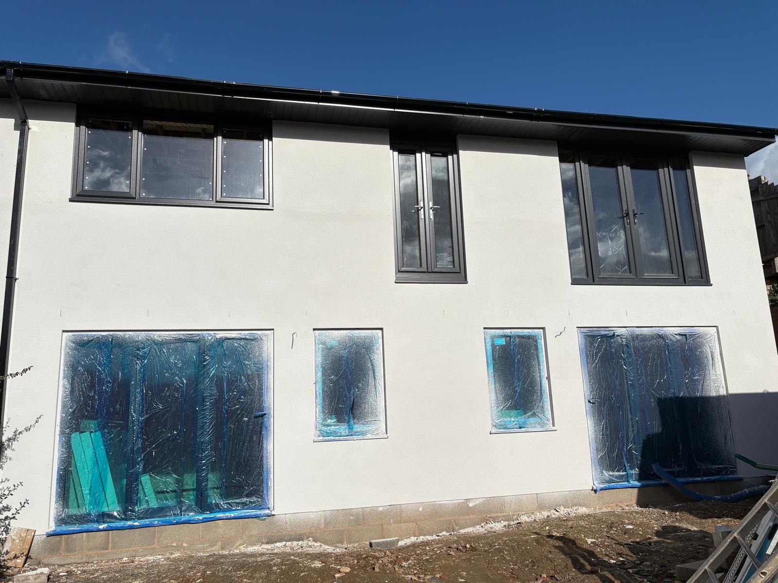 White building with windows, some covered in blue plastic, on a sunny day.