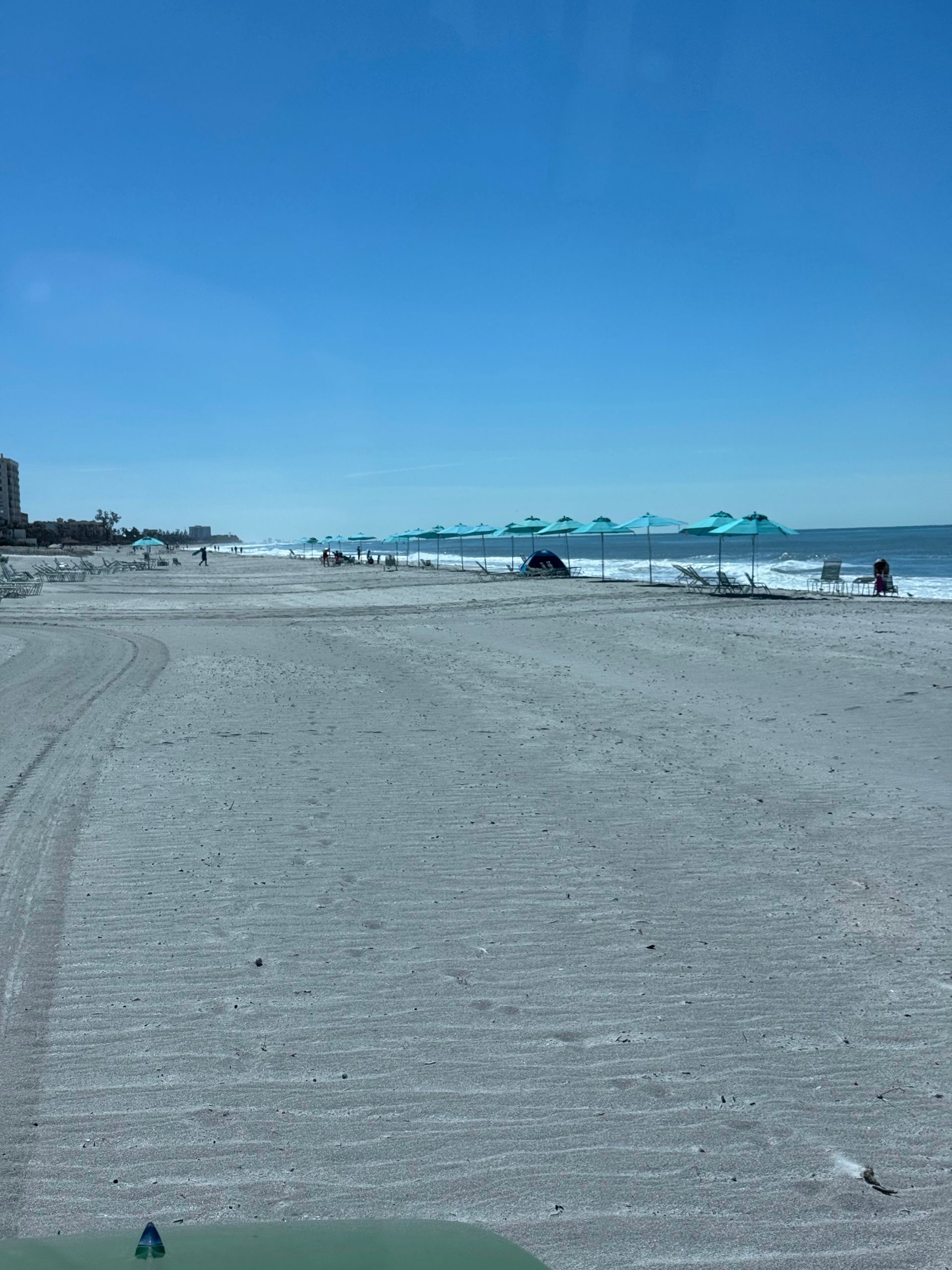 Beach scene with light blue umbrellas, white sand, and blue sky.