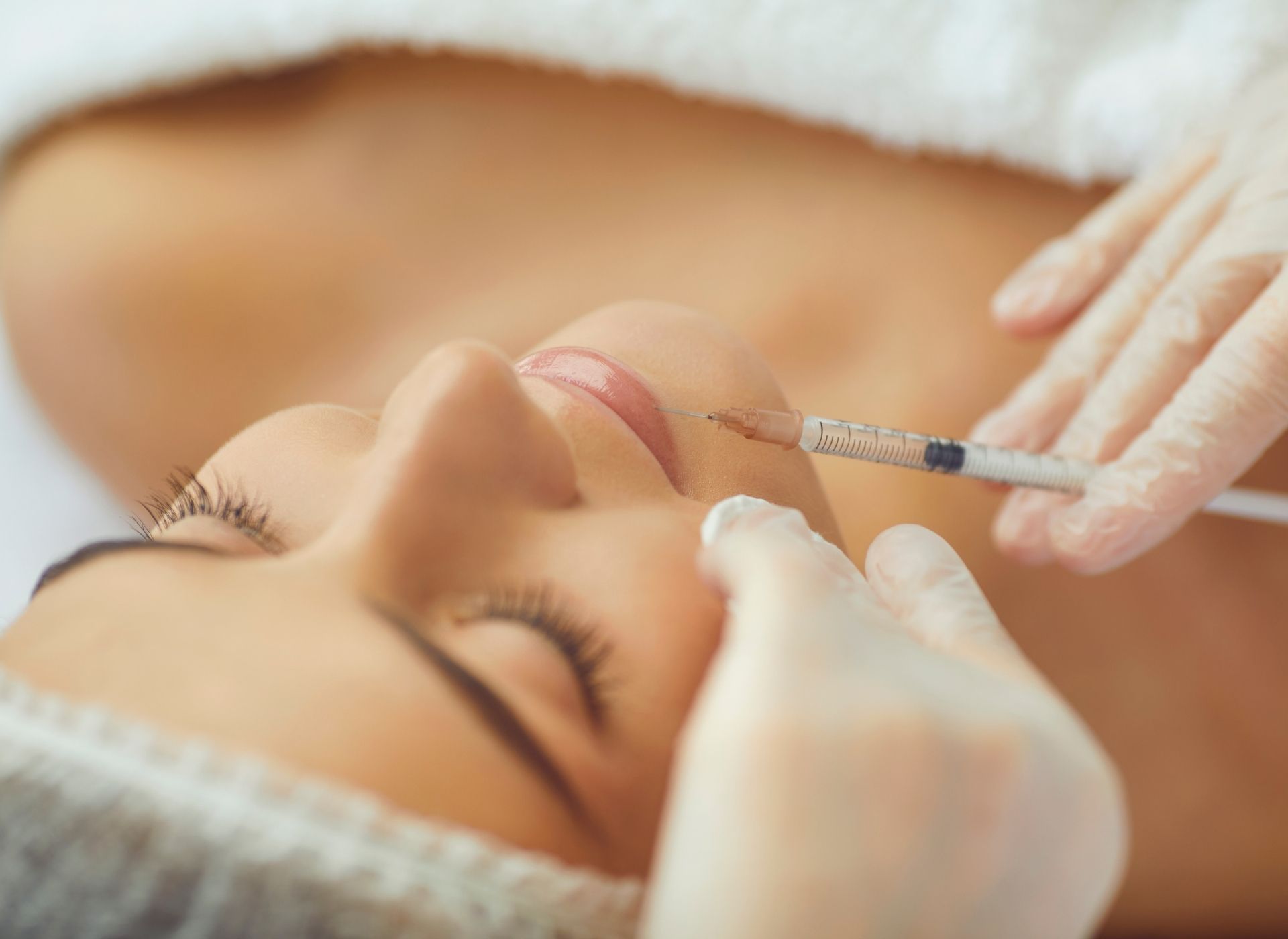 Person receiving facial injection, performed by gloved hands.