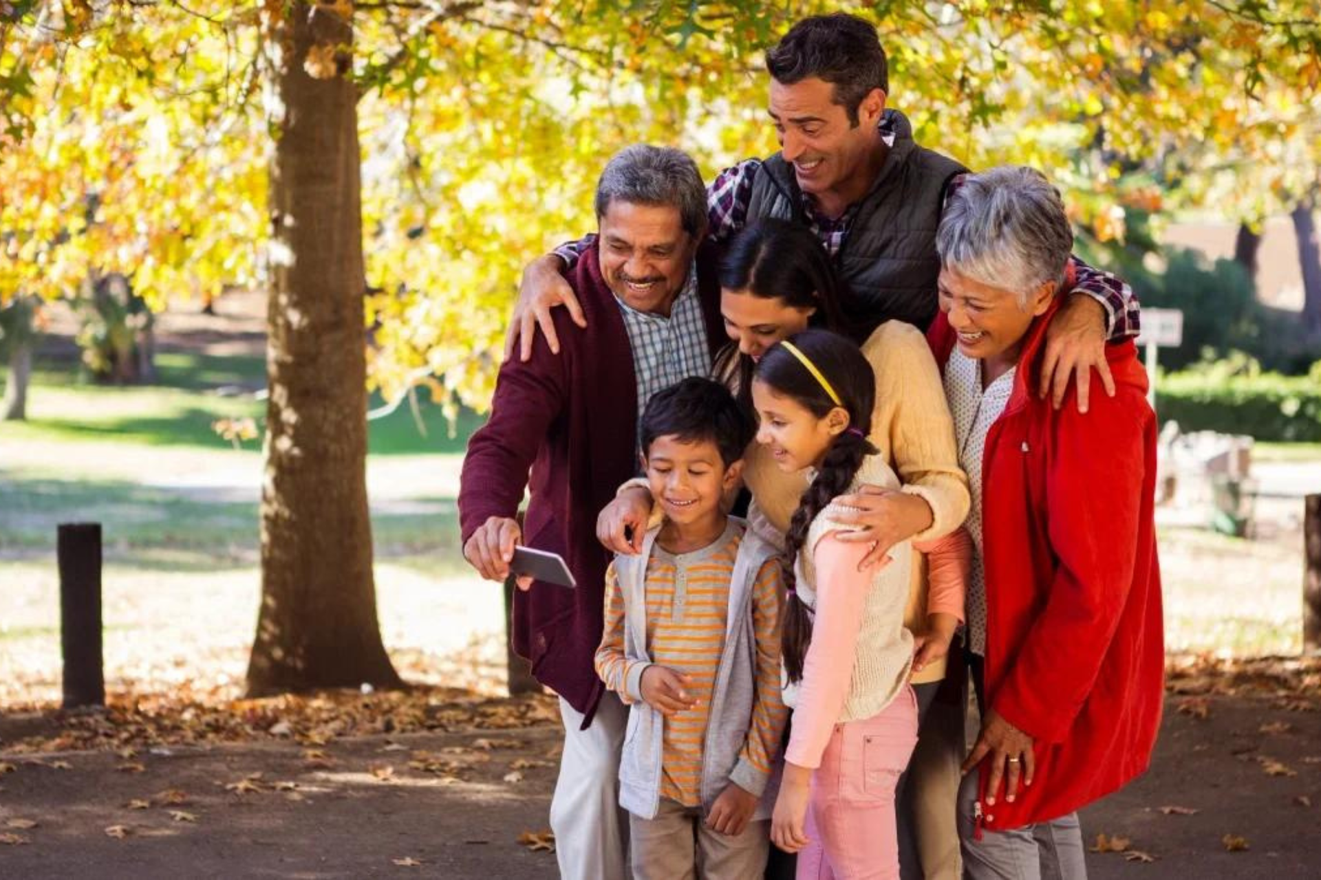 A large family is posing for a picture in a park.