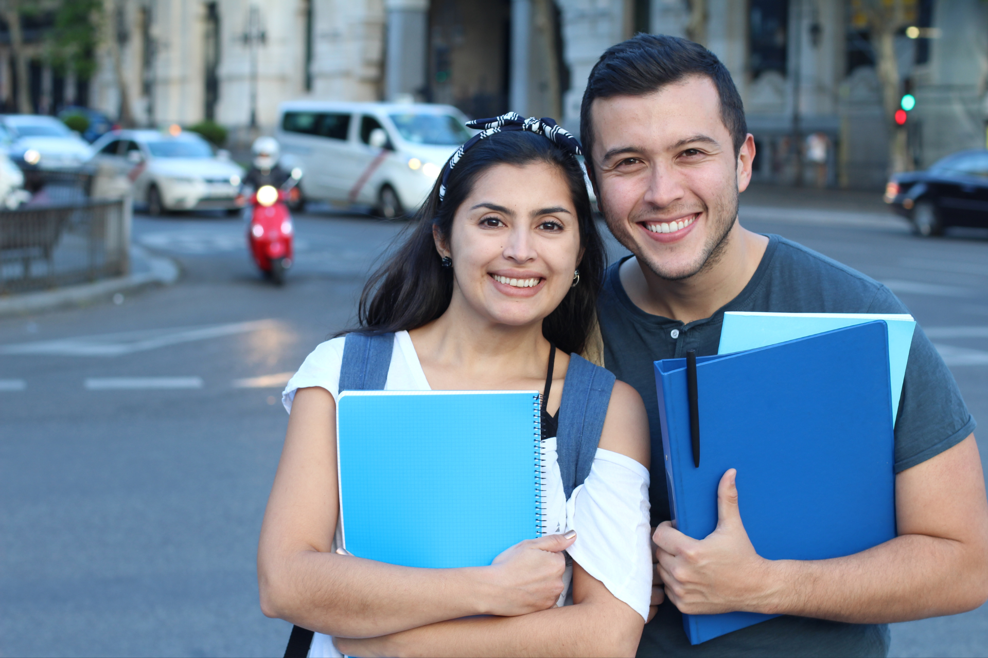 A man and a woman are standing next to each other holding books and smiling.