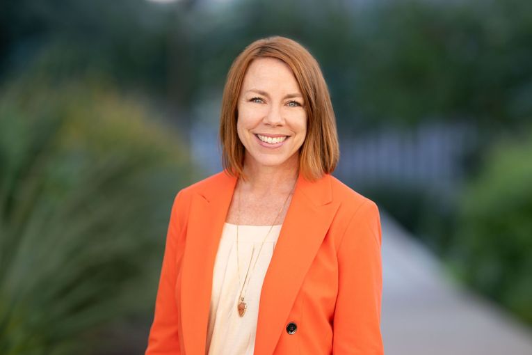 A woman is wearing a striped jacket and smiling for the camera.