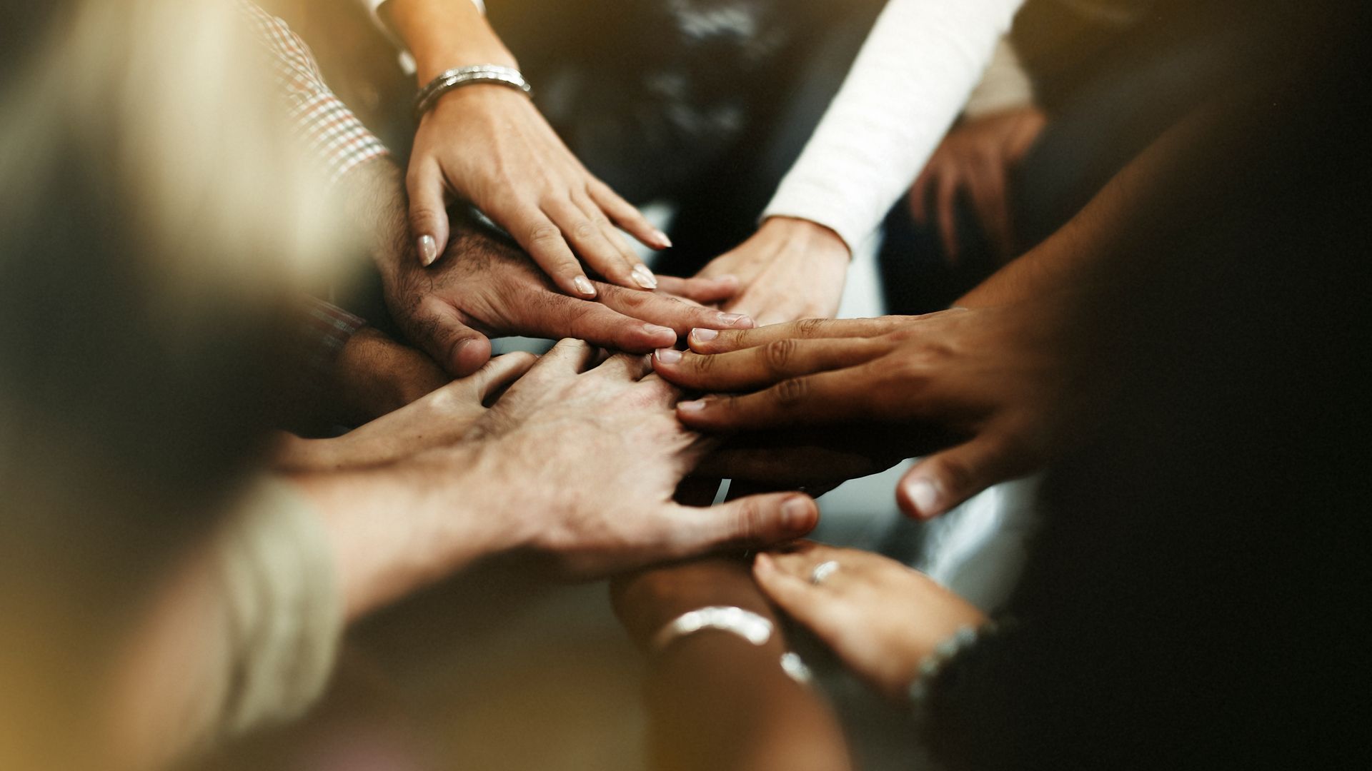 A group of people are putting their hands together in a circle.