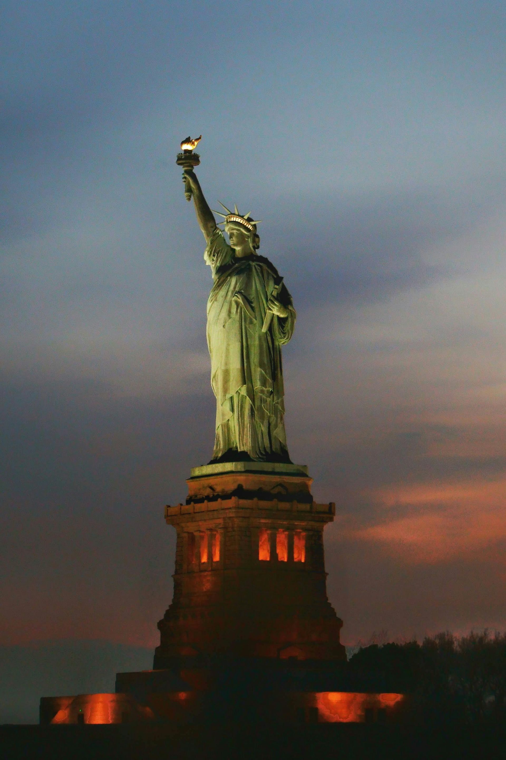 The statue of liberty is lit up at night