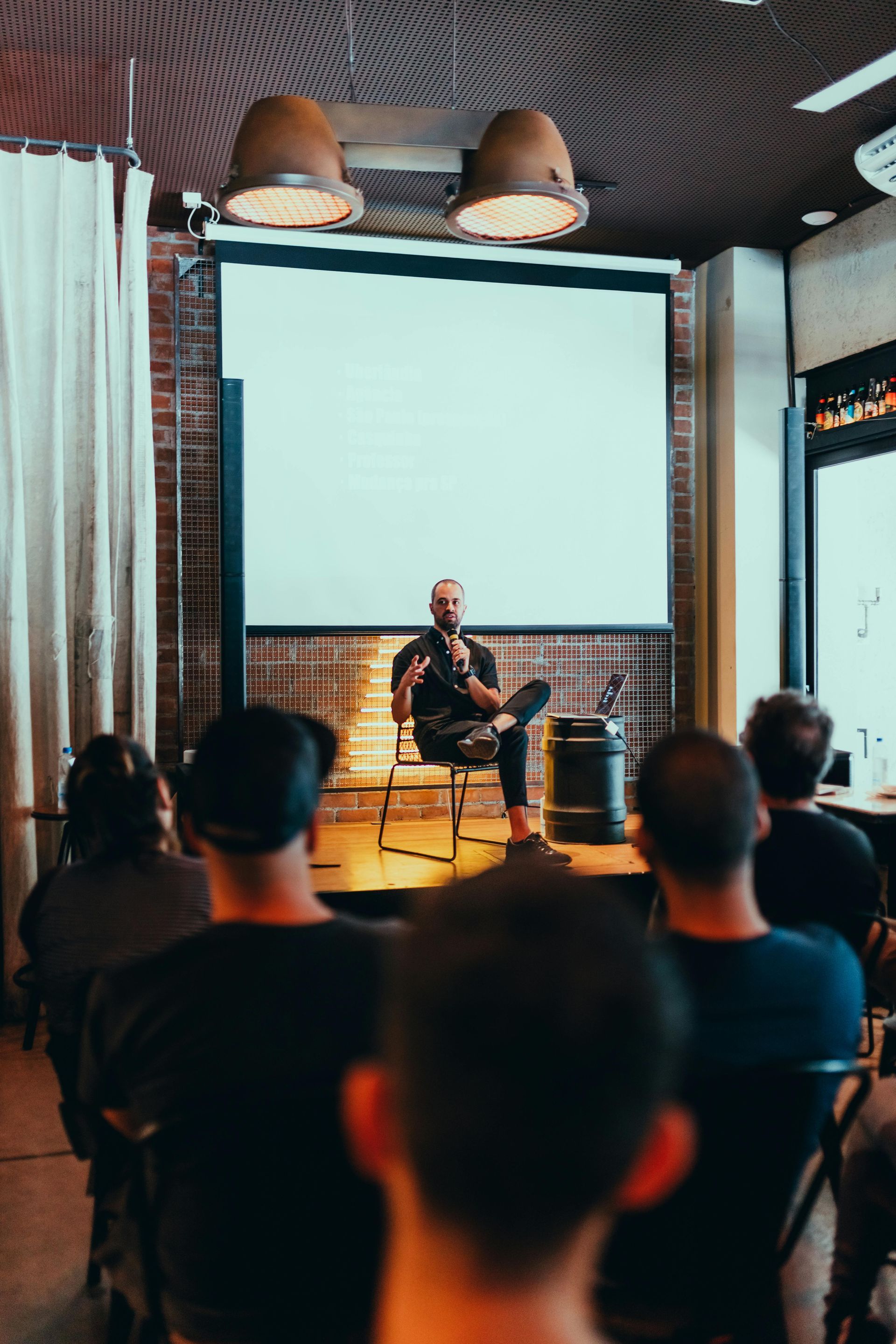 A man is giving a presentation to a group of people in front of a projector screen.