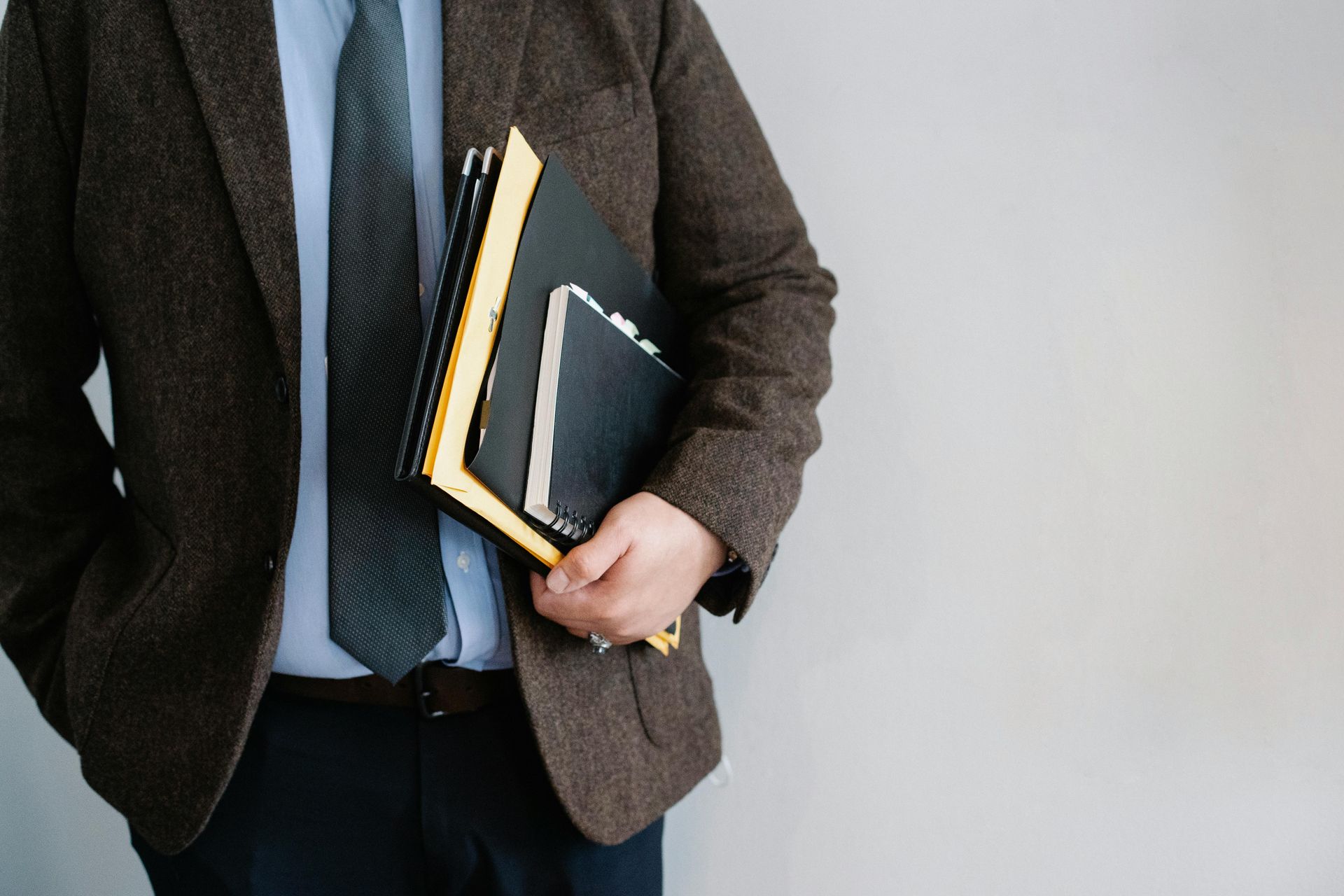 A man in a suit and tie is holding a stack of books.