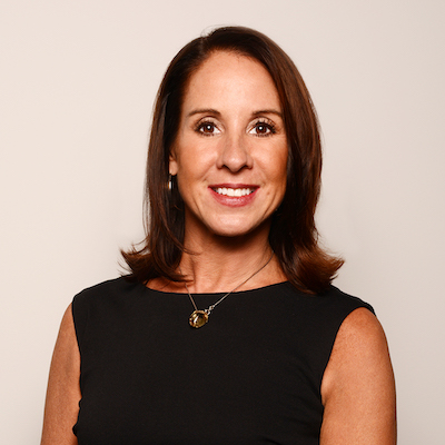 A woman with red hair is wearing a hat and earrings.