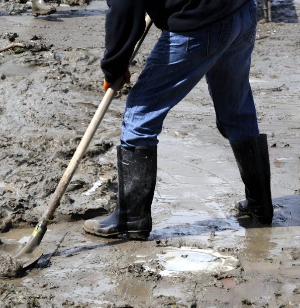 A Person Wearing Black Boots is Digging in the Mud — Premier Building QLD In Speewah, QLD