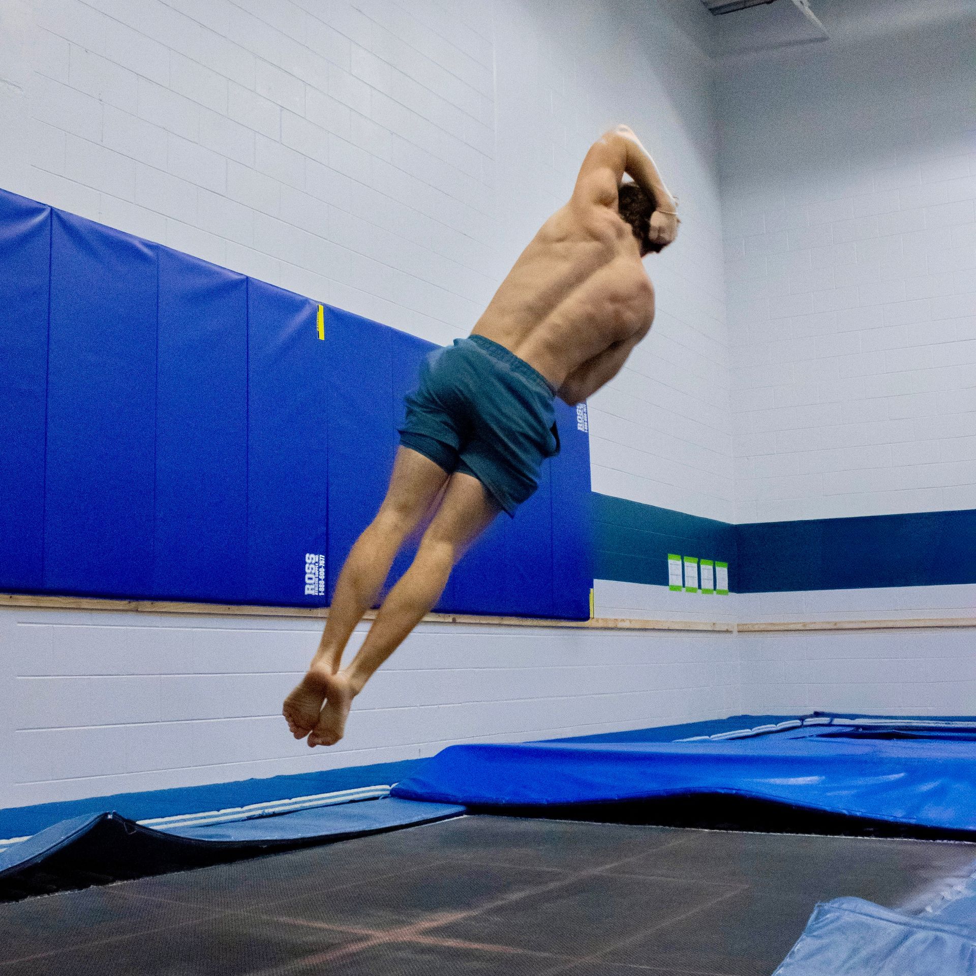 A man is watching a girl jump on a trampoline.