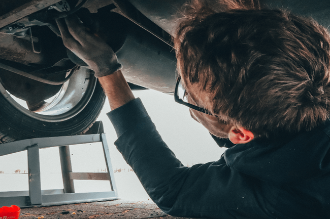 a mechanic under a vehicle doing a repair
