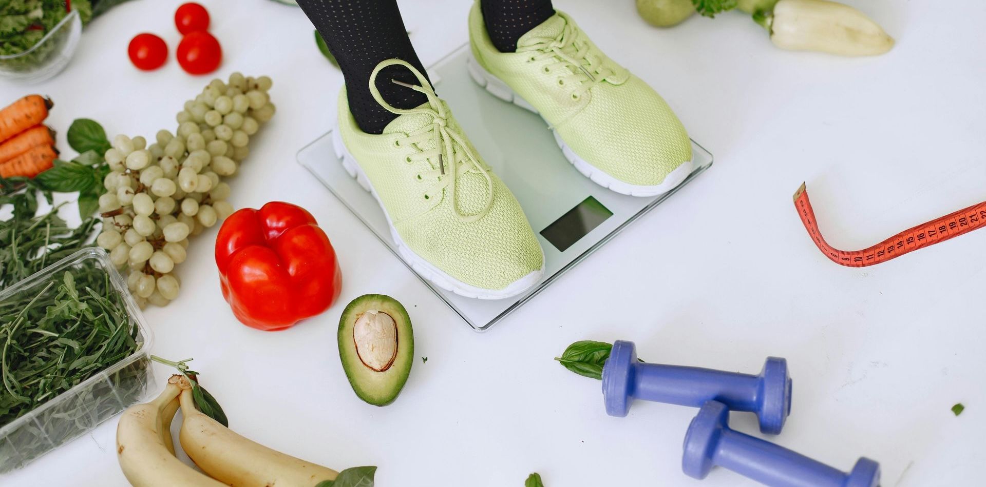 A person is standing on a scale surrounded by fruits and vegetables.