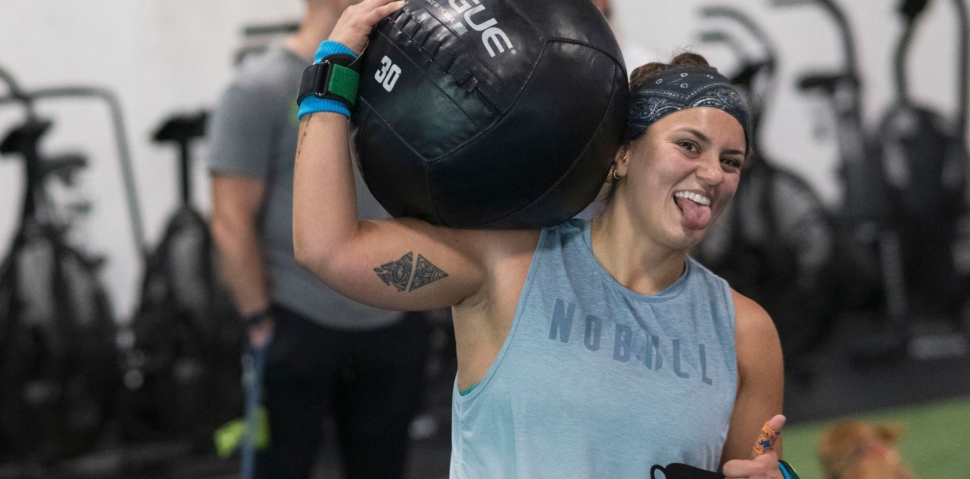 A woman is carrying a large ball on her shoulders in a gym.