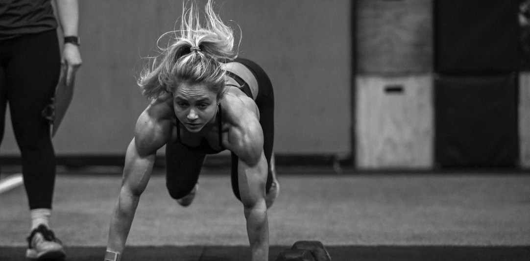 A black and white photo of a woman doing push ups in a gym.